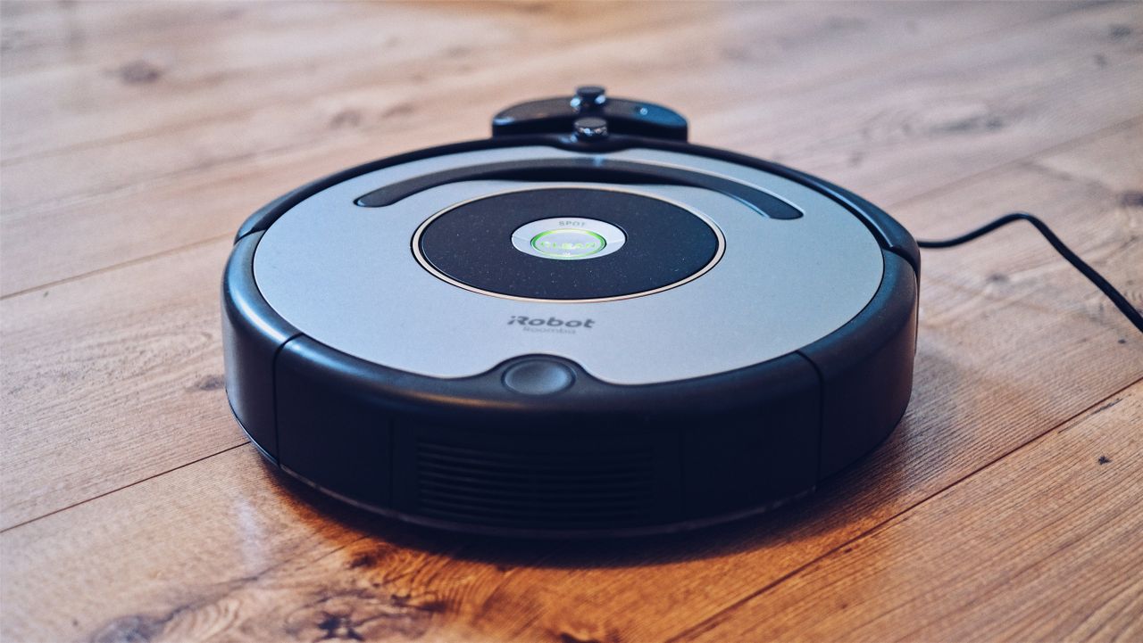 collection-04 Close-up of a robotic vacuum cleaner operating on a hardwood floor, showcasing modern cleaning technology.